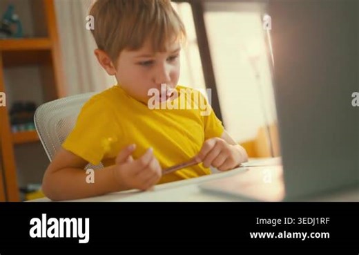 Curious preschooler sitting at a desk, learning online and interacting with a laptop screen Stock Video Footage - Alamy