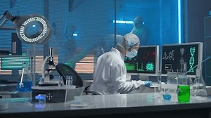 Medical development laboratory. A female scientist types on a keyboard and enters research data. A female researcher against backdrop of a modern laboratory with test tubes, flasks and a microscope.