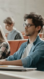Handsome Hispanic Student Uses Laptop Listening Lecture at the University, Raises Hand and Asks Lecturer a Question. Multi Ethnic Group of Students. Video Footage with Vertical Screen Orientation 9:16