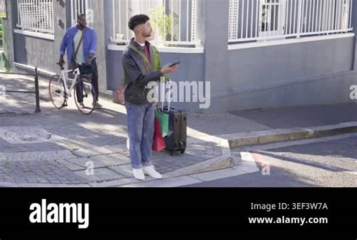 African American man and woman at curb holding phone and luggage crossing after cyclist passing. Suitcase, bags, crosswalk, smartphone, street, urban, sunny Stock Video Footage - Alamy