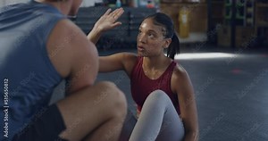 Motivated female exercising with her personal trainer or coach in gym. Inspired active fit woman training her core strength in a fitness center. Motivated athletic lady using a ball to workout