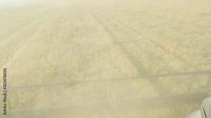 A combine harvester goes through a field and harvests grain. A close up front view from inside of the machine.