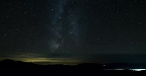 Time Lapse of The Milky Way Galaxy Moves Above the Mountains and Clouds on a Starry Night