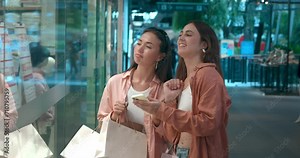 Women viewing storefronts in mall side view discussing shopping Storefronts showcase fashion joy. Storefronts mirrors of happy life stylish clothes Embracing fashion joyful exploration. Stock Video