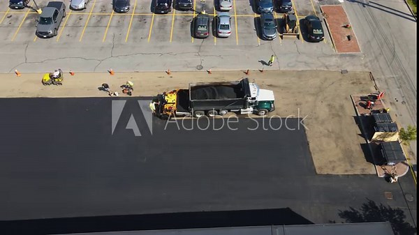 Work Crew applying new Asphalt to a car park. Looking down from above.