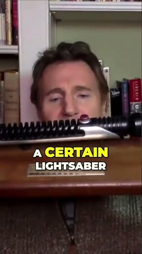 Liam Neeson shows off Qui-Gon's lightsaber from Star Wars: Episode 1