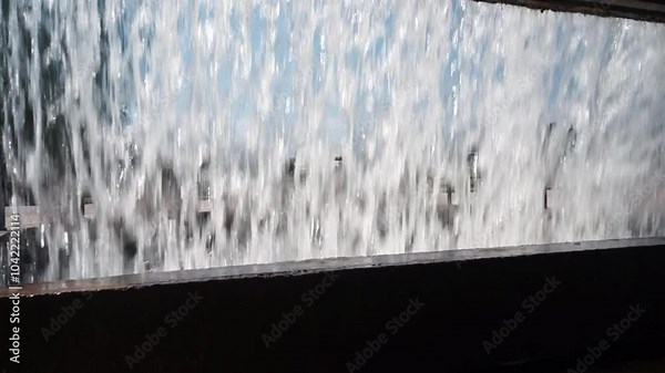 Cascading waterfall, with blurred background and shimmering light reflections creating a dynamic, fluid scene