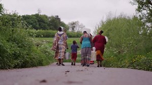 African family members of different generations work together to get water. In slow motion.