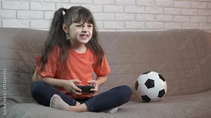 Play controller in hands. A stressed playfull child hold a controller and play football on screen.