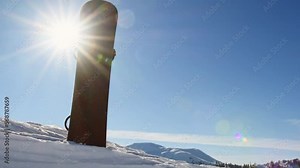 Black snowboard in snow with Beautiful mountains and fresh snow particles. Winter ski resort off piste background. Close up texture. Backcountry snowboarding