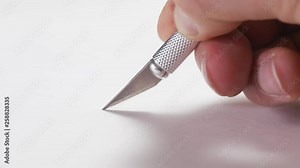 Using a scalpel to cut a straight line on a cardboard piece.