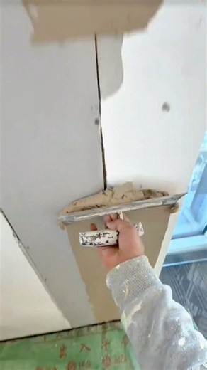 Applying smooth drywall mud with a trowel to expertly feather and finish the ceiling joints