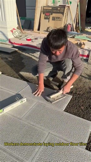 Workers demonstrate laying outdoor floor tiles