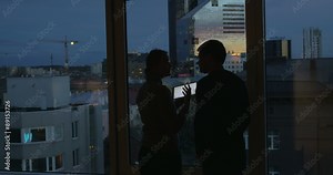 Couple using pad and enjoying view of evening city