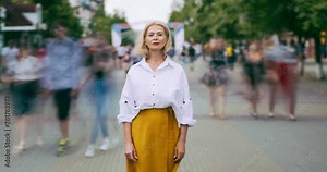 Time lapse portrait of good-looking mature woman in elegant clothing in street standing alone looking at camera with serious face. People, life and summer concept.