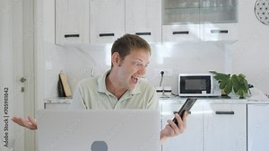 Angry mad man screaming, yelling and arguing talking on smartphone while working on laptop online at home. Upset shouting on mobile phone. Annoyed freelancer crying into the phone Stock Video