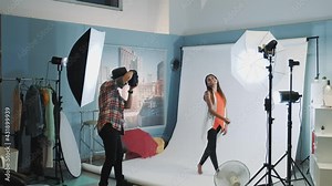 Photo shoot backstage: attractive african model posing in studio with modern photo equipment