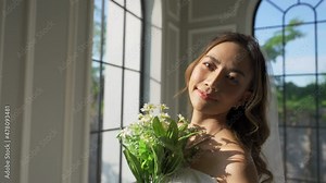 4K Portrait of young beautiful woman bride in wedding dress holding bouquet in fitting room. Attractive female bride, marriage and wedding ceremony marriage concept.