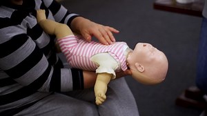 Practicing reanimation of infants. Medic shows tehnique with two fingers. Appropriate methods of first medical help.
