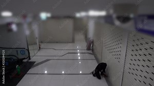 Sneaky cat burglar sneaks in to the shopping center at night to break into stors as seen from the cctv security camera