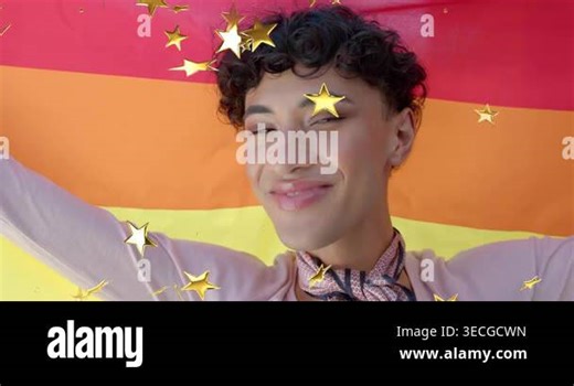 Man raising arms turning smiling by rainbow flag as gold stars falling across him celebrating pride Stock Video Footage - Alamy