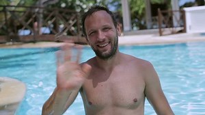 Man waving to the camera and swimming