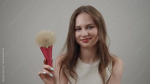 A young woman smiles joyfully while playfully holding a creative ice cream cone brush, blending fun with art Stock Video