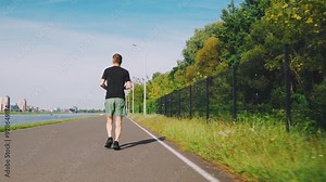 Running track, runner man running in city park. Unrecognizable man, back view. Running, cardio training. Runner actively training. Sports, increasing vital energy. Run, sportswear, healthy lifestyle