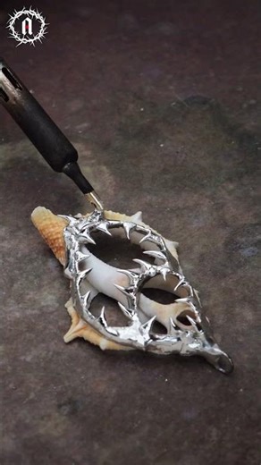 A seashell crowned in silver fangs, a piece that's sharp, untamed, and impossible to ignore.