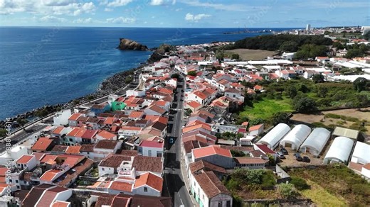 Sweeping aerial photograph of Ponta Delgada coastline on São Miguel Island with volcanic landscape and urban expansion.