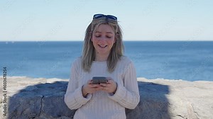 Caucasian woman flirting on phone. Mid aged person writing a text message outdoors.
