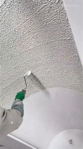 applying textured paint on ceiling using roller creating even pattern with consistent pressure