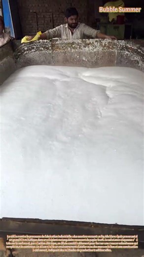 Production de mousse : des ouvriers traitant un matériau blanc dans un grand conteneur