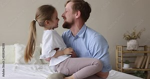 Pretty little girl enjoy funny playtime with loving father seated on his laps, play together in cozy bedroom, relish leisure and communication feel happy. Fatherhood, unconditional love, family ties