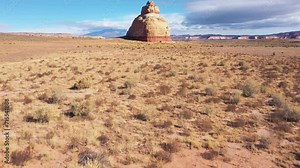 High Church Rock butte tower monument of beige cliffs rocks stands alone in dried desert. Tourist travel western Usa in Utah. Beautiful landscape of nature. Aerial fly forward. Geological layers rock