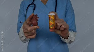 Red heart symbol of pill in hands of cardiologist. Heart disease prevention and healthcare