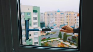 Polishes windows with sponge. View through the window cleaning washing windows by special mop