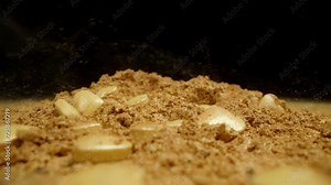 Slow-motion: heart-shaped candies fall into golden powdered sugar, against a black background.