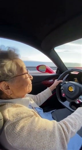 Grandma sits in a Ferrari and drives along the highway