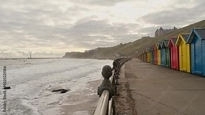 Slow motion footage of waves rolling in at Whitby beach on the North Yorkshire coast. Captured from the promenade at high tide on an overcast autumn morning