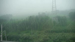 Speeding train travel,scenery outside window.Villages plains tree farmland.high-voltage lines wires.