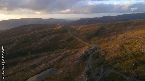 Drone shot flying over the Applecross pass road over the Bealach na Bà pass in the Scottish highlands at sunset.