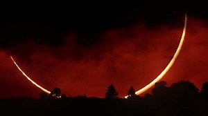 Epic cinematic shot of a huge crescent sun during a solar eclipse at sunset. Captured near the horizon with forest silhouette and intense colors. Scenic view for nature, science, or dramatic visuals.