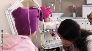 Nail masters doing pedicure for two pretty little girls in professional salon
