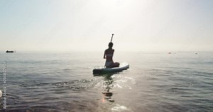 Beautiful athletic woman stand up paddle boarding, healthy active fitness lifestyle