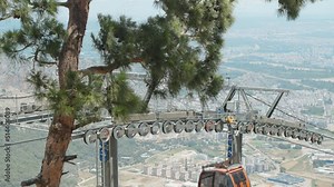 Cable car, funicular. Rollers on poles close-up, the funicular passes by. Trees and mountains.