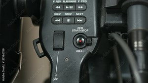 Pressing the top handle record button on an ENG video camera.