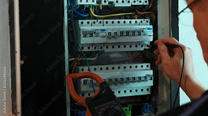 Electricians hands testing current electric in control panel. Electrician engineer work tester measuring voltage and current of power electric line in electical cabinet control.