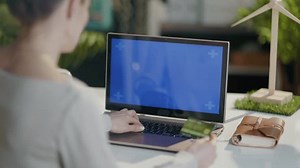 Seen from behind modern woman with laptop and credit card buying online in modern office.