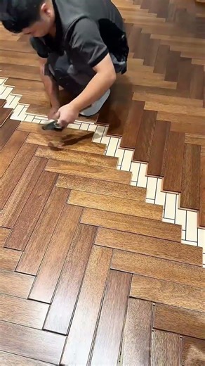 installing herringbone pattern wood flooring with precise craftsmanship and mallet on indoor surface